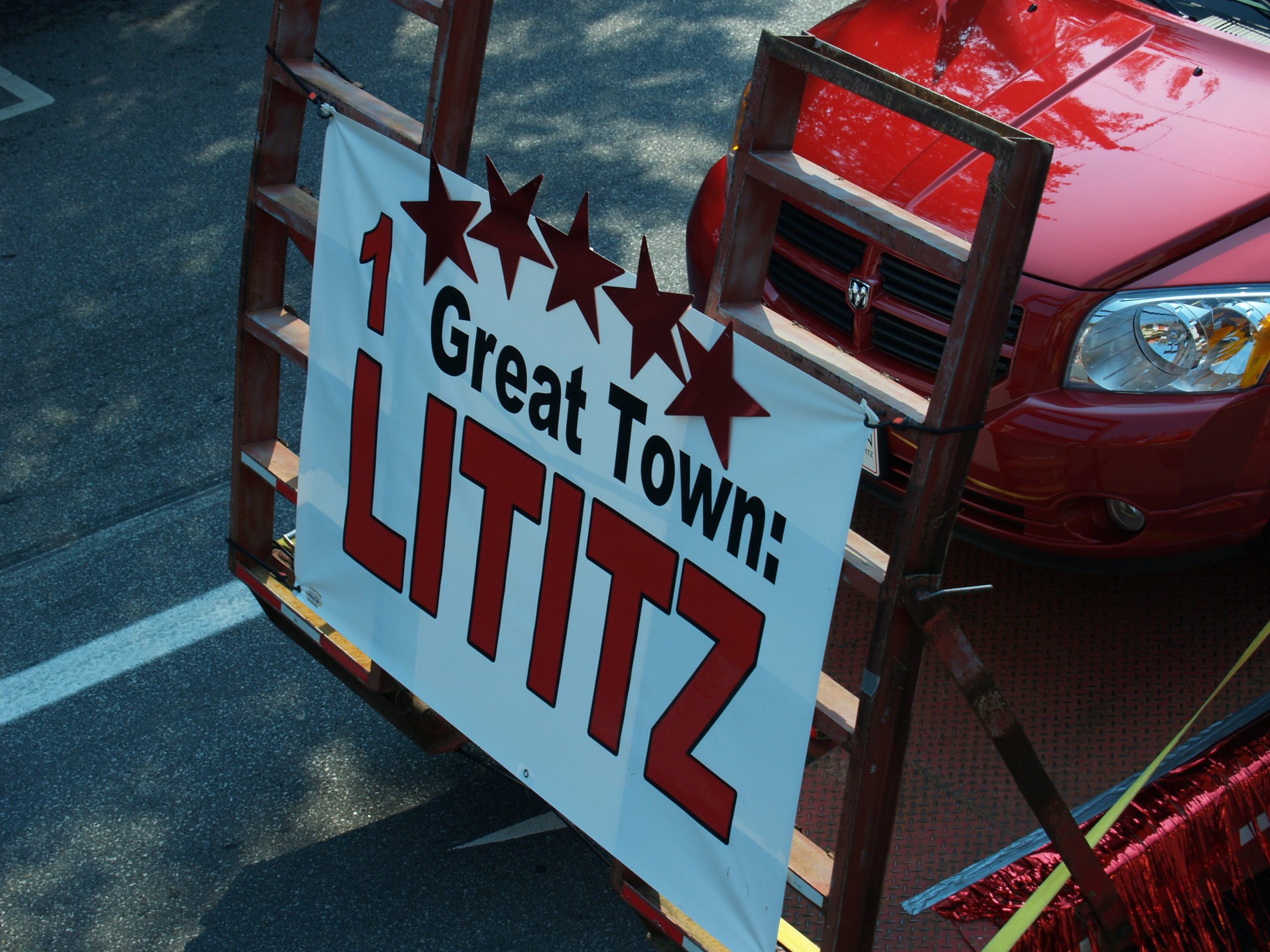 Sign on front of red car in parade that reads "1 Great Town Lititz"